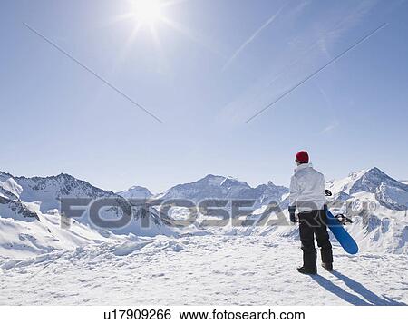 Stock Photograph - man with snowboard on top of mountain. Fotosearch