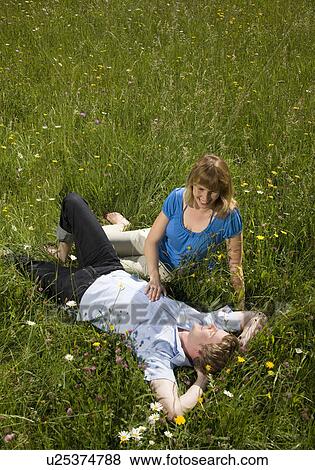 Stock Photo - man, woman lying in grass with flowers. Fotosearch