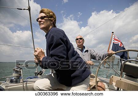 Stock Photograph - Mature couple sailing yacht. Fotosearch