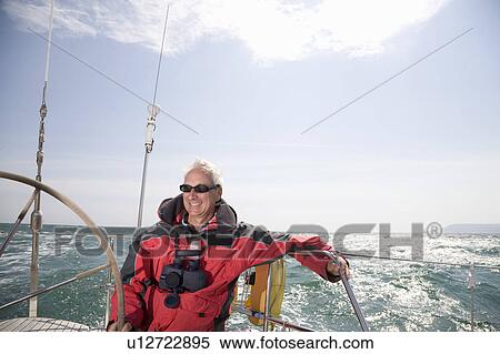 Stock Photography - Mature man sailing yacht. Fotosearch