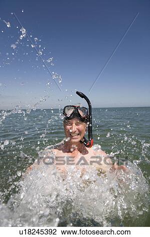 Mature man with snorkel splashing water View Large Photo Image Stock Image - Mature man with snorkel splashing water. Fotosearch