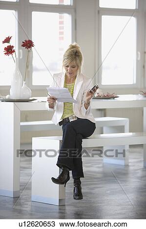 Stock Image - Mid-40 businesswoman sitting on a bench. Fotosearch