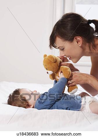 Stock Image - Mother and baby playing with teddy bear. Fotosearch