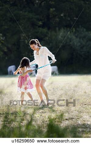 Stock Image - Mother and daughter playing with hoop. Fotosearch