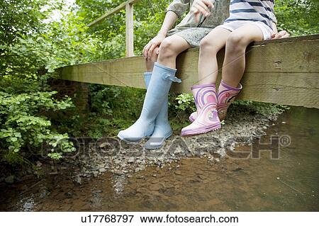 Stock Photo - Mother and daughter sitting on bridge. Fotosearch
