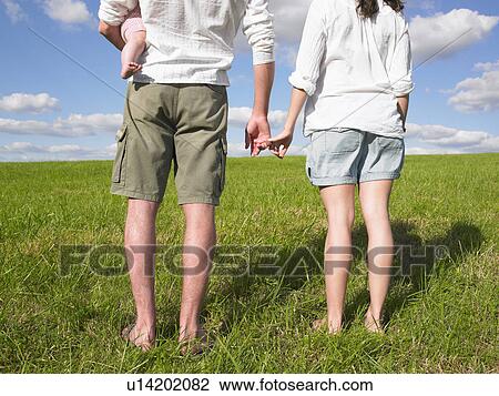 Stock Image - mother, father and baby in field. Fotosearch