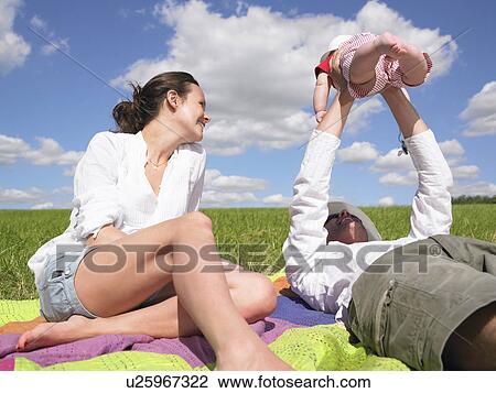 Stock Image - mother, father and baby in field. Fotosearch