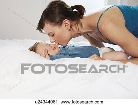Stock Image - Mother kissing sleeping baby. Fotosearch
