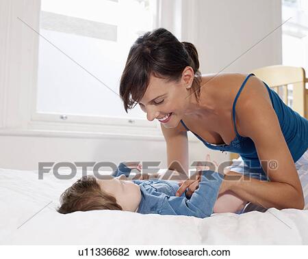 Mother smiling at baby lying on bed View Large Photo Image Stock Image - Mother smiling at baby lying on bed. Fotosearch
