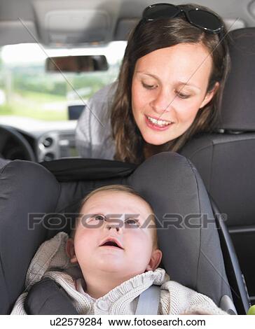 Picture - mother watching baby in car seat. Fotosearch