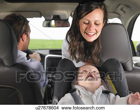 Picture - mother watching baby in car seat. Fotosearch