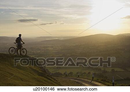 Stock Photograph - Mountain biker looking at the sunset.. Fotosearch