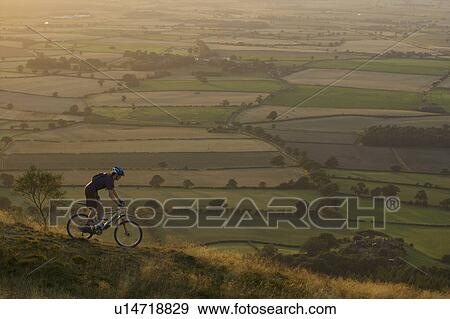 Stock Photo - Mountain biker riding down a hill.. Fotosearch