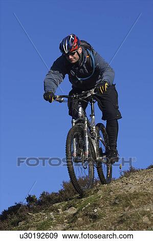 Stock Photo - Mountain biker riding down a hill.. Fotosearch