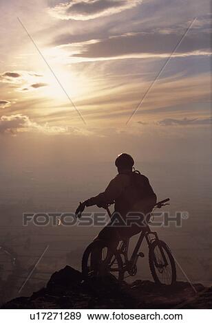 Stock Photo - Mountain biker taking in the sunset. Fotosearch