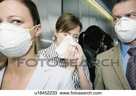 Stock Image - People in a lift during a health alert. Fotosearch