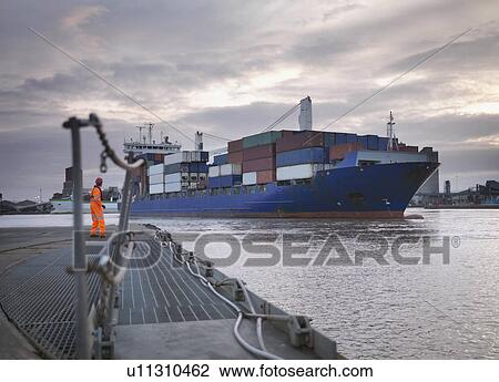 Stock Image - Port Worker And Ship Coming Into Port. Fotosearch