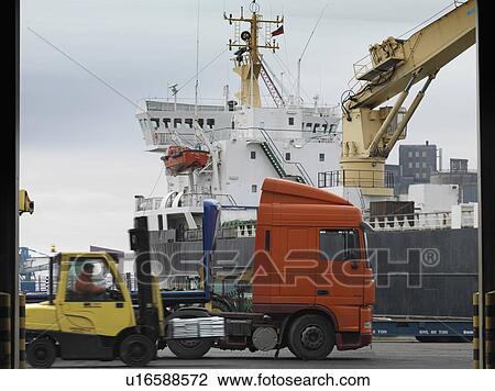 Stock Image - Port Worker In Forklift With Ship. Fotosearch