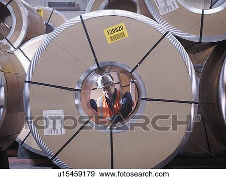 Stock Photo - Port Worker Inspecting Circular Cargo. Fotosearch