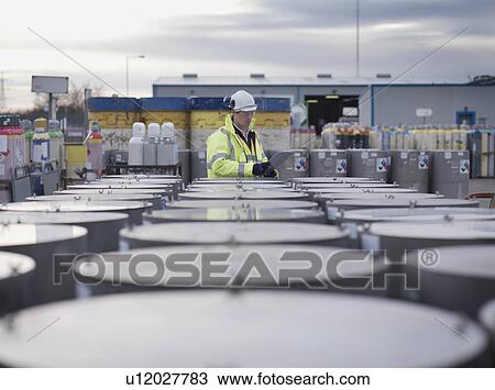 Stock Image - Port Worker Inspecting Cylinders. Fotosearch