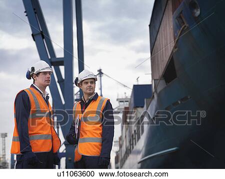 Stock Image - Port Workers Beside Loaded Ship. Fotosearch