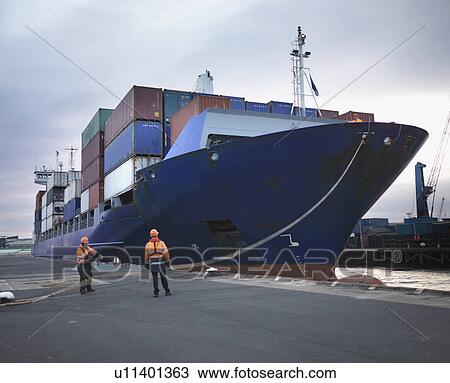 Stock Image - Port Workers With Loaded Ship At Port. Fotosearch