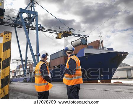 Stock Photo - Port Workers With Ship Being Loaded. Fotosearch