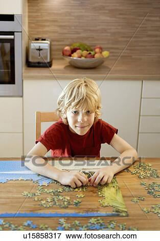 Stock Photo - Portrait of a boy doing a puzzle. Fotosearch