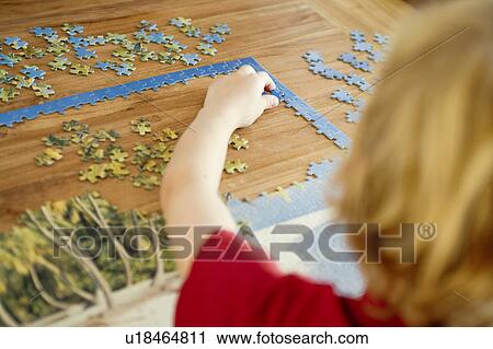 Stock Image - Portrait of a child doing a puzzle. Fotosearch