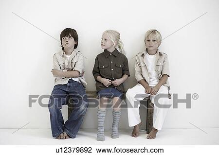 Stock Image - Portrait of two boys and a girl on bench. Fotosearch