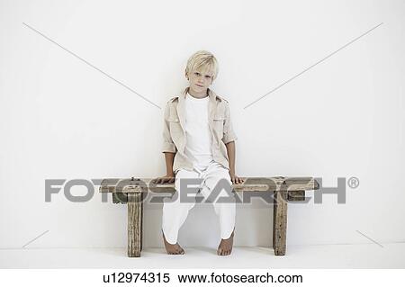 Stock Photography - Portrait of young boy on a bench. Fotosearch