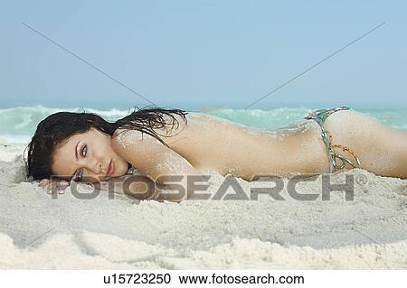 Stock Image - Portrait of young women lying on a beach. Fotosearch