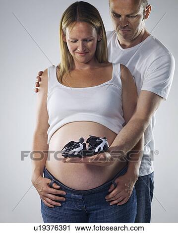 Stock Image - pregnant couple with baby football boots. Fotosearch