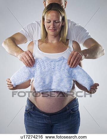 Stock Photograph - pregnant woman with man and baby clothes. Fotosearch