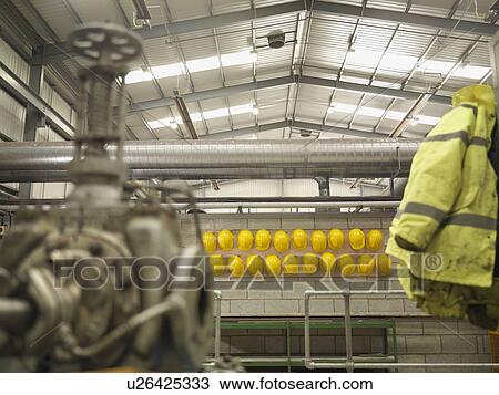 Stock Image - Rows Of Yellow Hard Hats And Jacket. Fotosearch