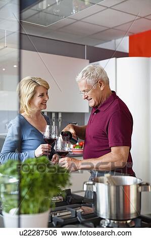 Stock Photograph - Senior Couple Drinking Wine in Kitchen. Fotosearch