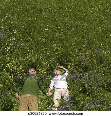 Stock Image - Senior couple lying in field of flowers. Fotosearch