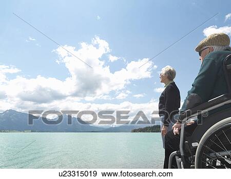 Stock Photo - Senior couple relaxing by lake. Fotosearch