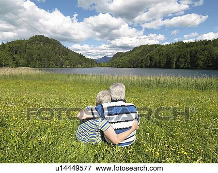 Senior couple sitting in field by lake View Large Photo Image Stock Photo - Senior couple sitting in field by lake. Fotosearch