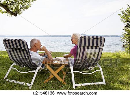 Stock Photograph - senior man and woman in deck chairs. Fotosearch