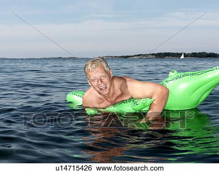 Senior man on inflatable crocodile View Large Photo Image Stock Photograph - Senior man on inflatable crocodile. Fotosearch