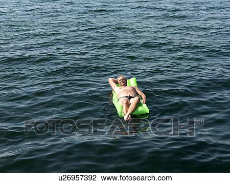 Stock Image - Senior man on inflatable mattress. Fotosearch