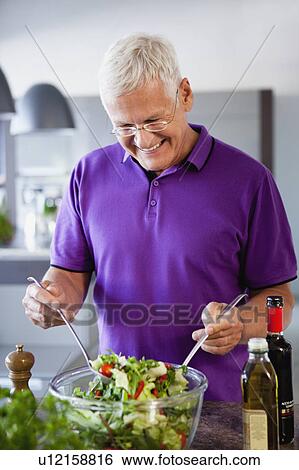 Stock Photograph - Senior Man Preparing Salad. Fotosearch