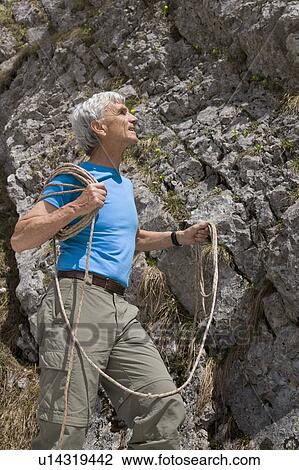 Stock Image - senior man with climbing rope at rock. Fotosearch