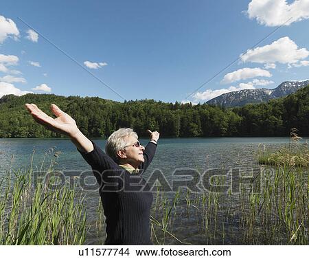 Senior woman standing by lake, side view View Large Photo Image Picture - Senior woman standing by lake, side view. Fotosearch