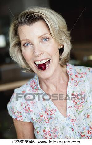 Stock Photograph - Senior Woman with Cherry between teeth. Fotosearch