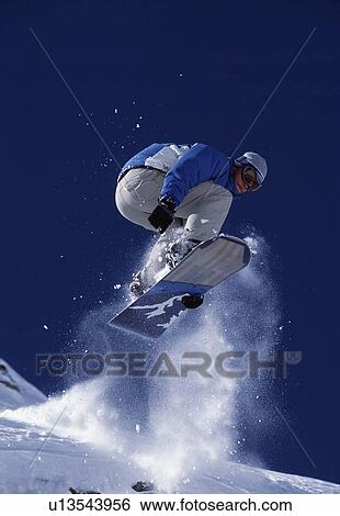 Stock Photograph - Snowboarder jumping into the air.. Fotosearch