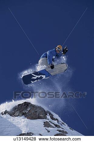 Stock Photo - Snowboarder jumping off a rock. Fotosearch