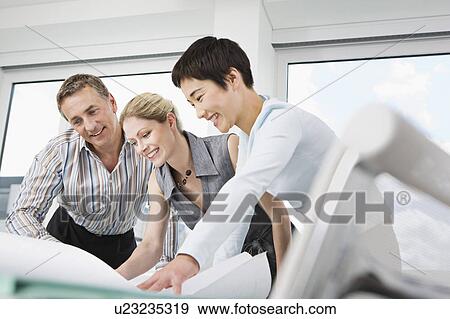 Three business people look at some plans View Large Photo Image Stock Photo - Three business people look at some plans. Fotosearch
