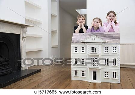 Stock Photography - Three children resting on a dollhouse.. Fotosearch